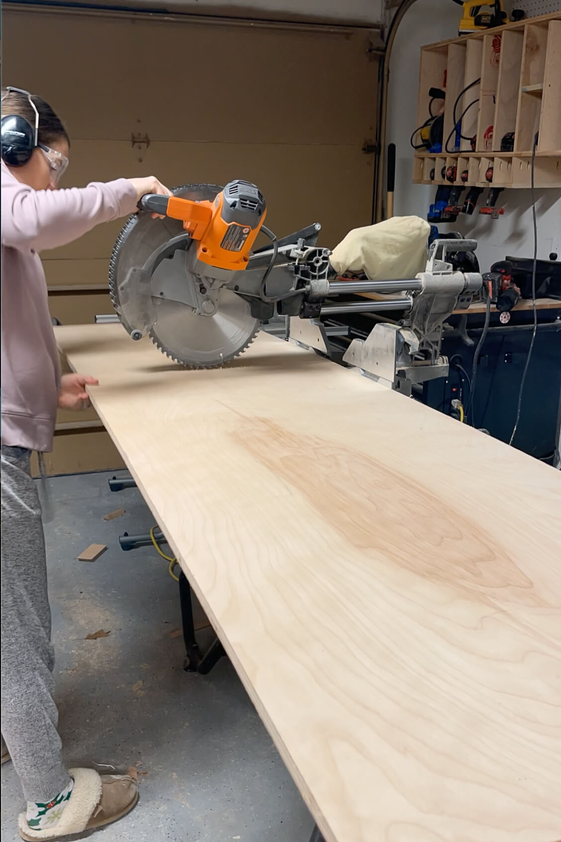 Using a miter saw to cut through a large sheet of plywood.